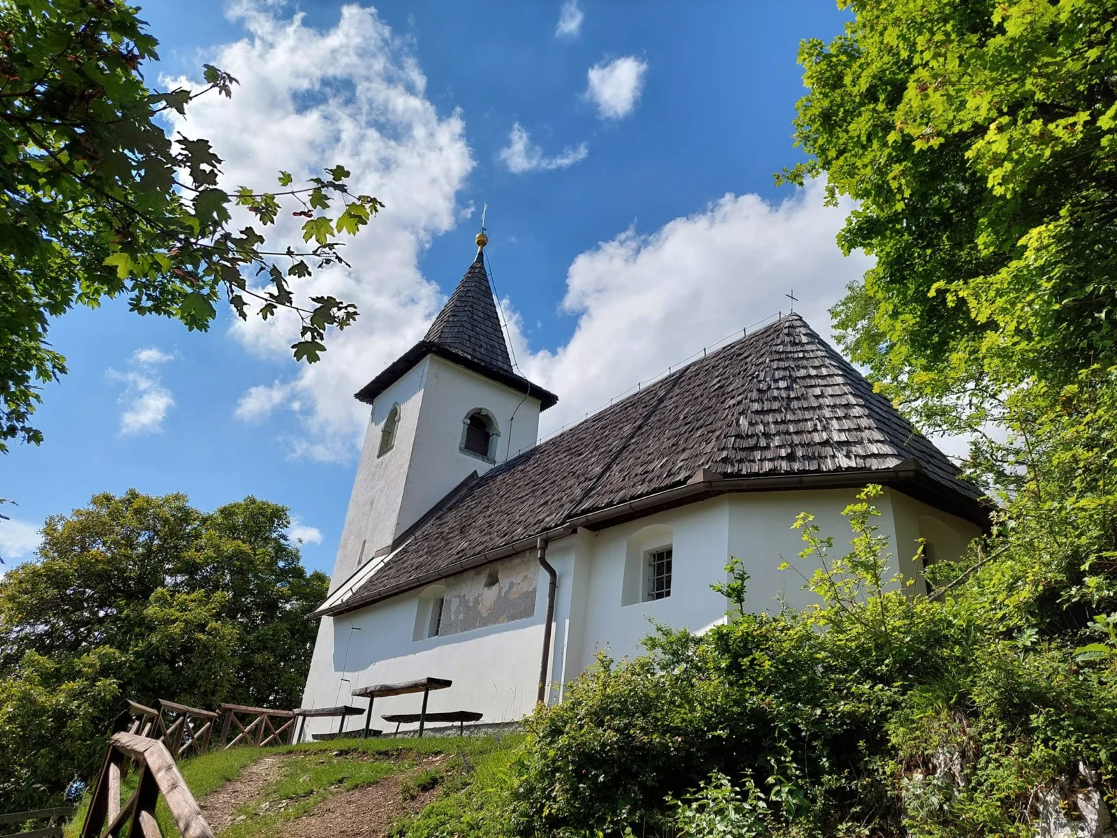 Cerkev sv. Jakoba nad Preddvorom med zelenimi drevesi